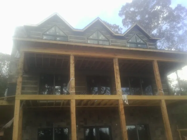 Dormers and porch framing on a large log home under construction — Roof Coating work by our crew in Plainville