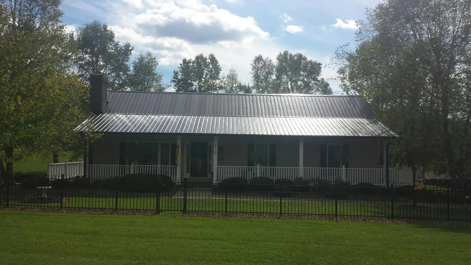 Gray metal roof on a brick ranch with a full width front porch — Gutter Guard Installation work by our crew in Plainville